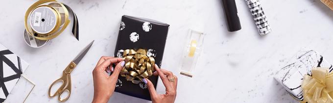 Ouro e fontes pretas do papel de embrulho pela indicação que inclui a fita, as curvas, o papel de envolvimento & o lenço de papel